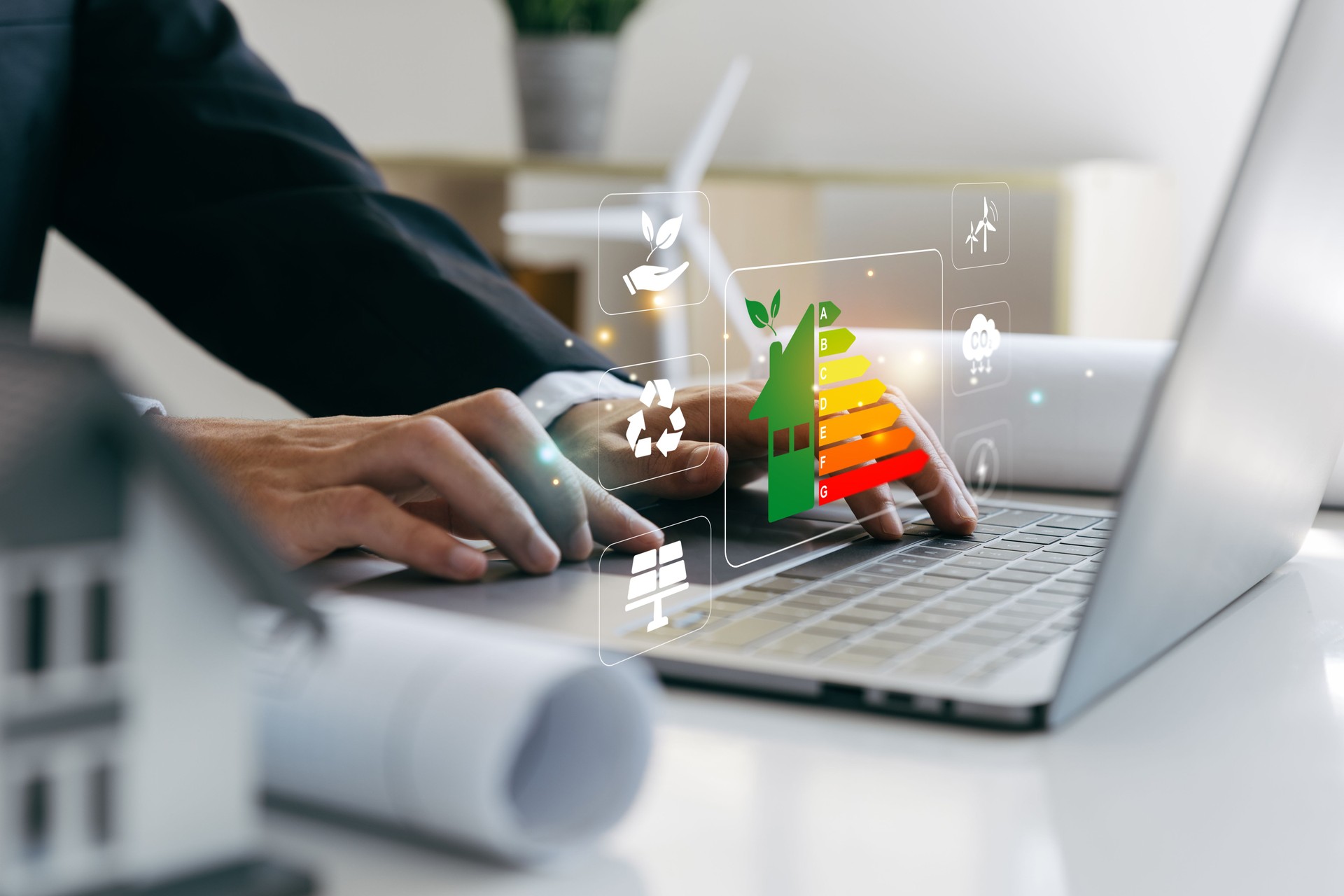 Hand of businessman using laptop with energy efficiency rating, ecological and bioenergetic house, efficiency scale.