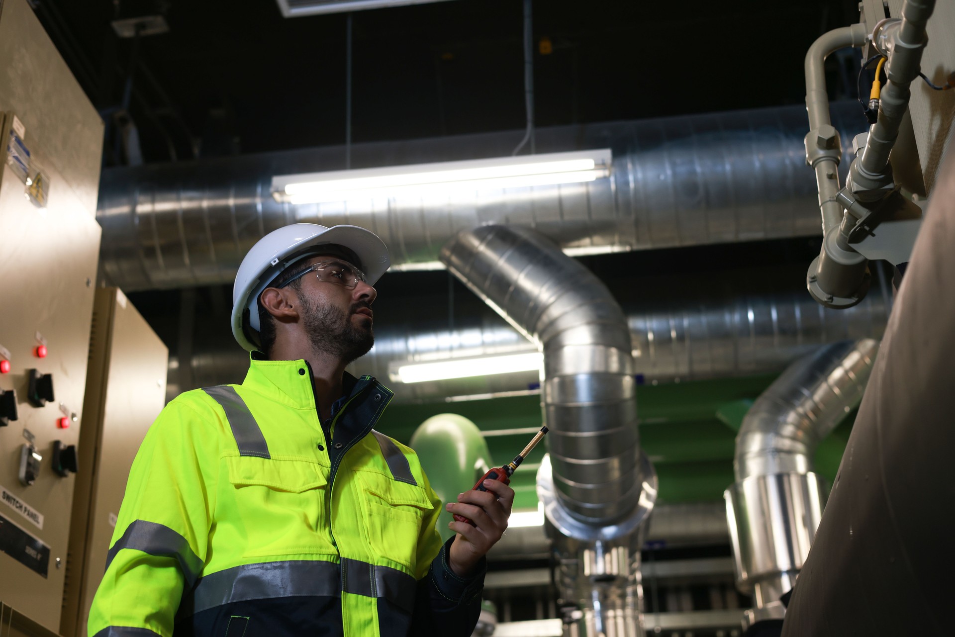 Specialist HVAC Industrial engineer with green safety jacket and PPE check piping and HVAC control system, maintenance service