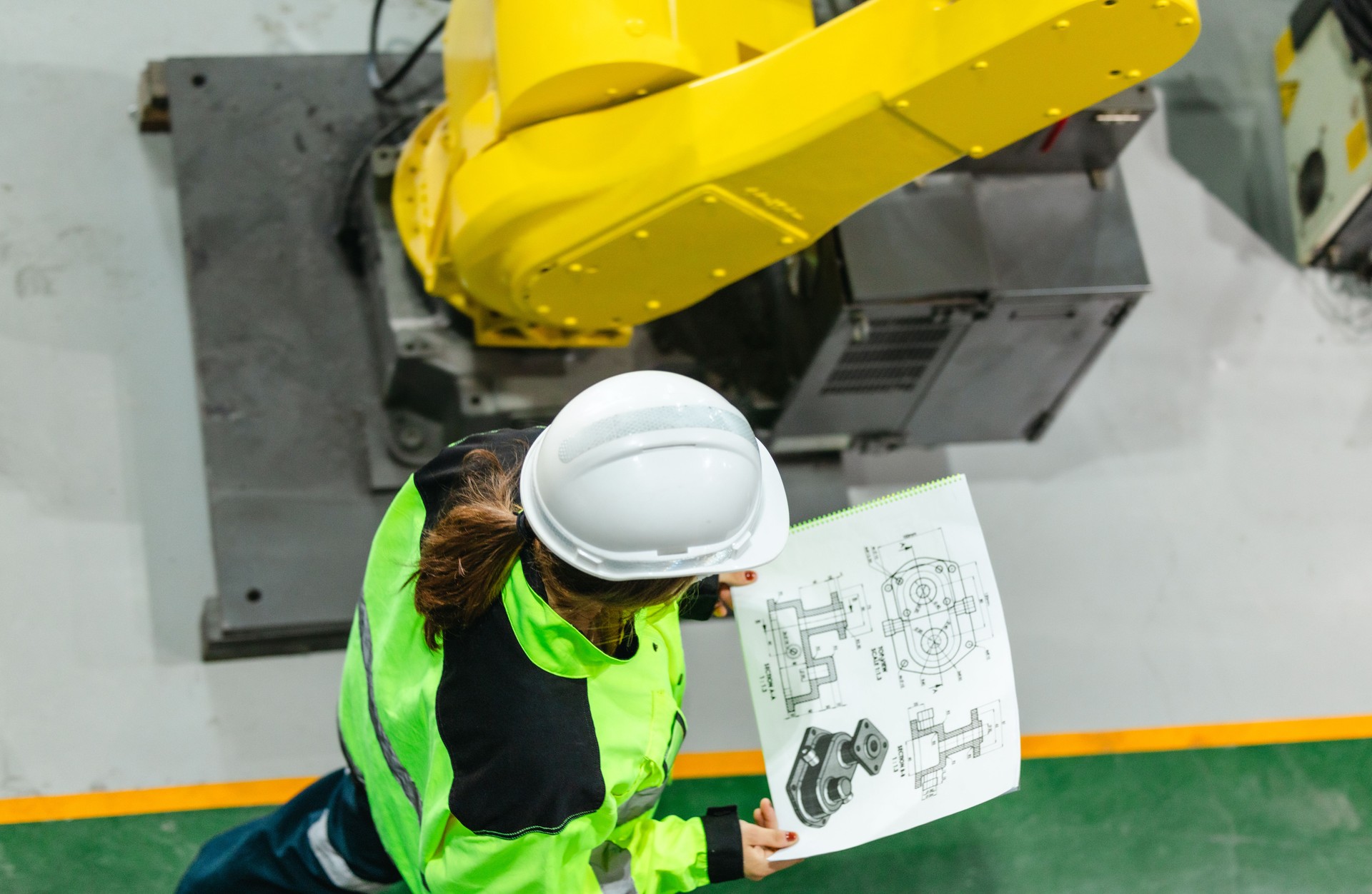 Engineer Reviewing Blueprint in Robotic Facility