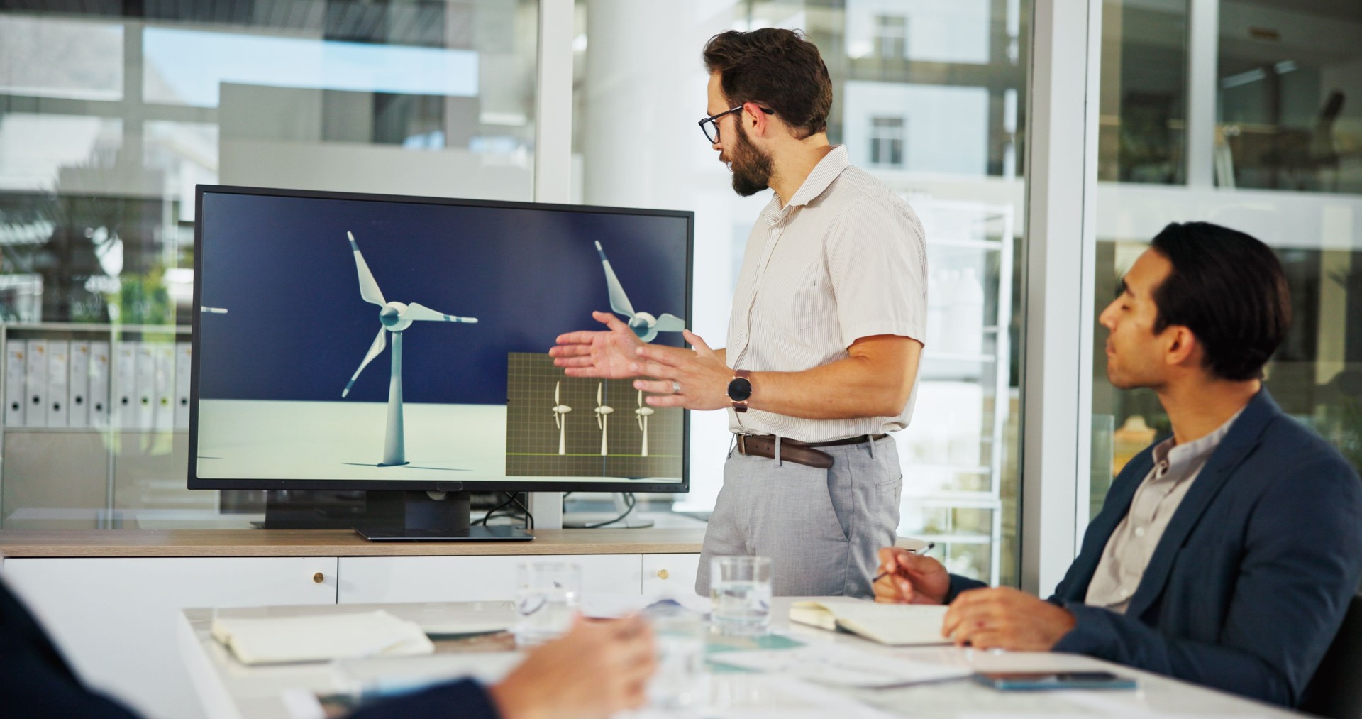 Businessman, meeting and screen with presentation for renewable or clean energy at conference. Man, employee or speaker talking to group with technology display of wind turbine for eco development