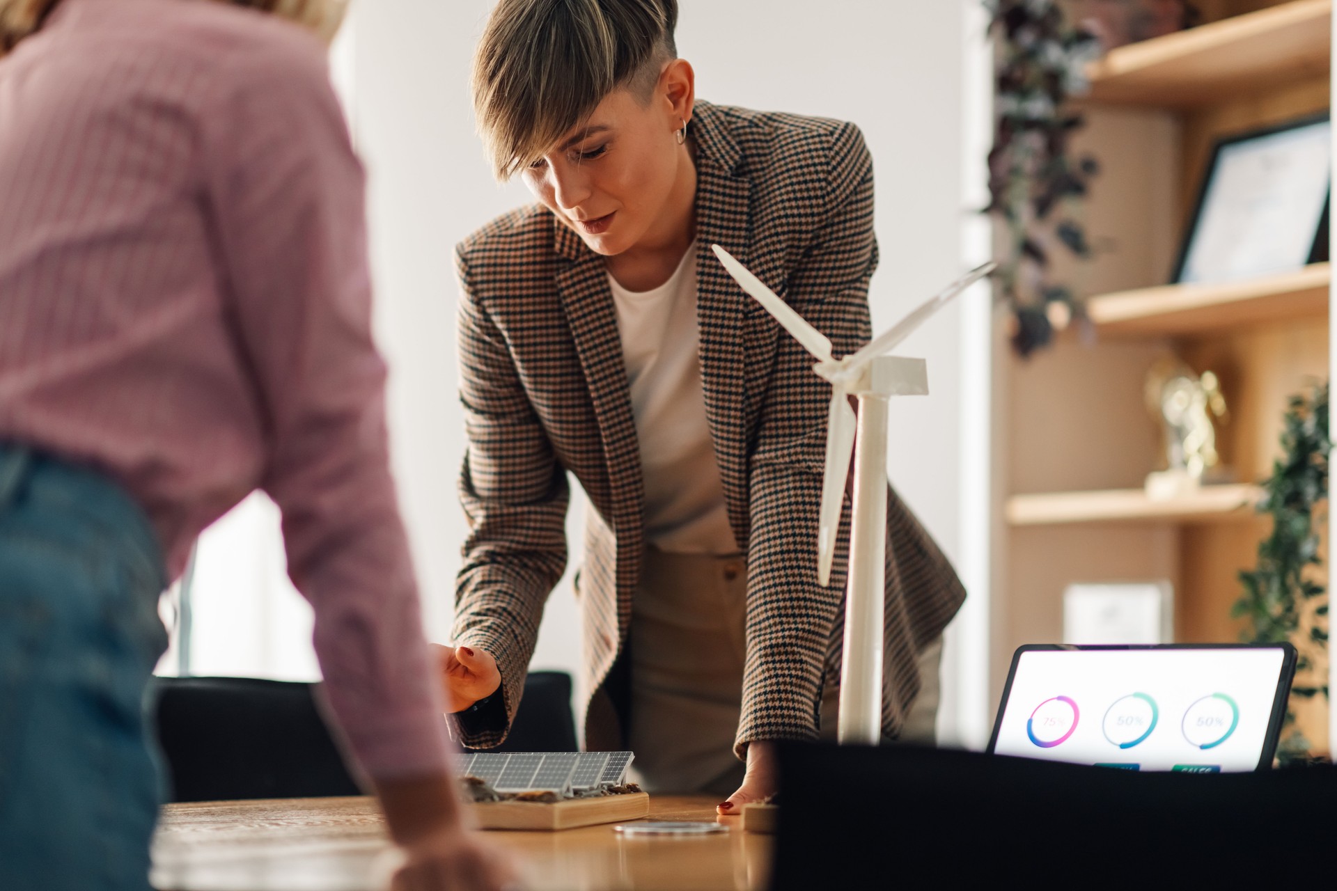 Engineers analyzing a renewable energy project with solar panel and wind turbine models